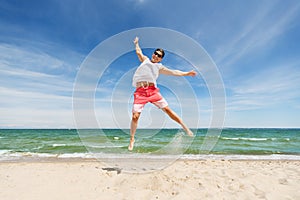 Smiling young man jumping on summer beach