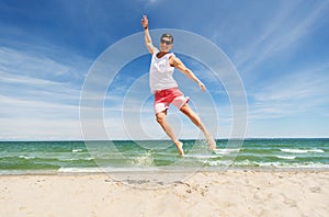 Smiling young man jumping on summer beach