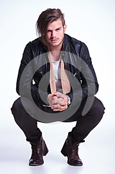 Smiling young man in leather jacket standing crouched photo