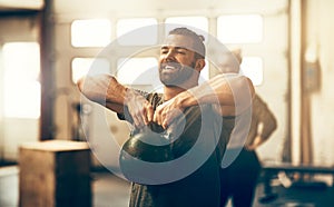 Smiling young man lifting a dumbbell while working out