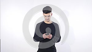 Smiling young man looking at his smart phone while text messaging isolated on white background