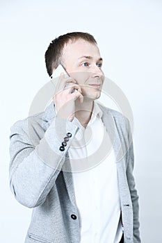 Smiling young man looking at his smart phone while text messaging on white