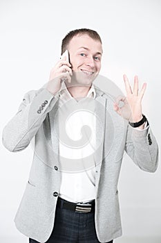 Smiling young man looking at his smart phone while text messaging on white
