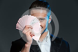 Smiling young man magician covered his face with playing cards