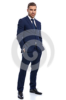 Smiling young man in navy blue suit holding hands in pockets
