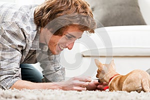 Smiling young man playing with a pet chihuahua