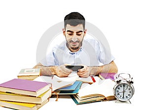 Smiling young man reading sms on mobile instead of doing homework