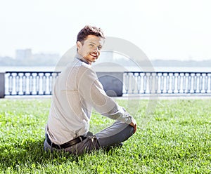 Smiling young man relax on the green lawn