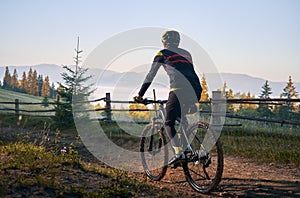 Smiling young man riding bicycle on mountain road.