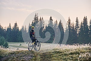 Smiling young man riding bicycle on mountain road.