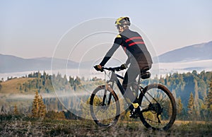 Smiling young man riding bicycle on mountain road.