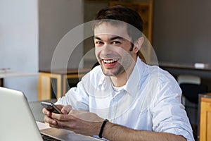 Smiling young man sending text message on mobile phone