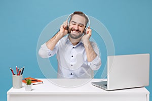 Smiling young man in shirt work at desk with pc laptop isolated on pastel blue background. Achievement business career