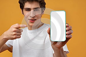 Smiling young man showing mobile phone blank white screen mockup to camera.