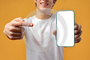 Smiling young man showing mobile phone blank white screen mockup to camera.