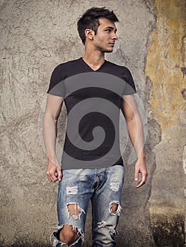 Smiling young man standing against concrete wall