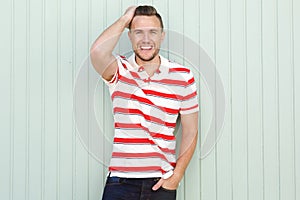 Smiling young man standing against green wall with striped shirt