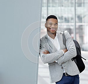Smiling young man standing at airport with bag