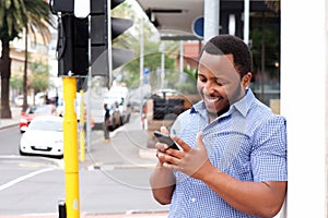 Smiling young man standing in city with cellphone