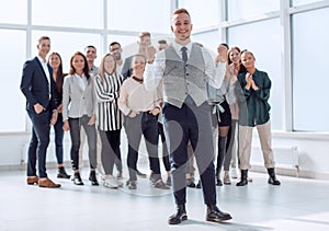 smiling young man standing in front of his colleagues