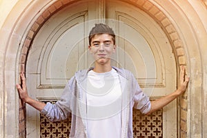 Smiling young man standing in front of an old door