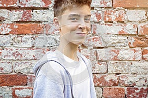 Smiling young man standing in front of a red brick wall