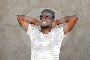 Smiling young man standing with hands behind head