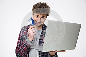 Smiling young man standing with laptop