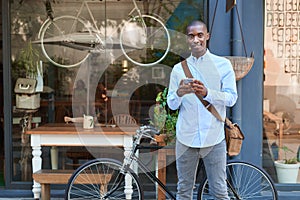 Smiling young man standing in the street reading text messages