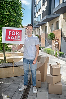 Smiling young man standing with a table for sale