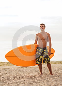 Smiling young man with surfboard on beach