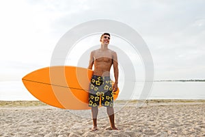 Smiling young man with surfboard on beach