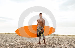 Smiling young man with surfboard on beach