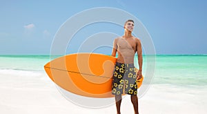 Smiling young man with surfboard on beach