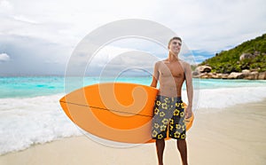 Smiling young man with surfboard on summer beach