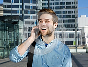 Smiling young man talking on mobile phone at airport