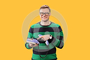 Smiling young man talking on the phone. Man holds purple phone in his hands and calling on a yellow background. Studio photo