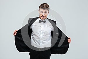 Smiling young man in tuxedo taking off his jacket