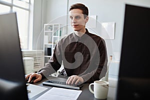 Smiling young man using computer in clean office workplace