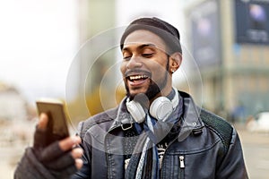 Smiling young man using smart phone outdoors at urban setting