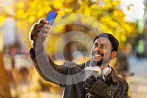 Smiling young man using smart phone outdoors at urban setting