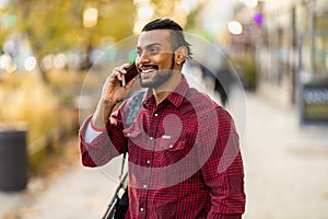 Smiling young man using smart phone outdoors at urban setting