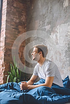 smiling young man waking up in his bed during morning time