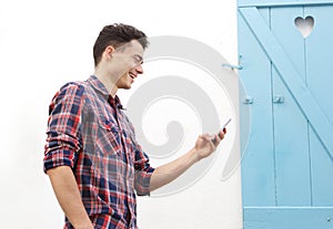 Smiling young man walking outside with mobile phone