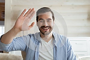 Smiling young man wave to camera talking on video call