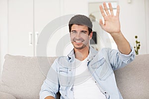 Smiling young man waving hand looking at camera making video call