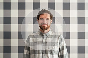 Smiling young man wearing a checkered shirt matching his wallpaper