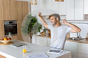 smiling young man with wide arms sitting at kitchen table with digital