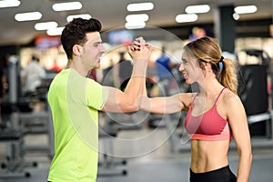 Smiling young man and woman doing high five in gym