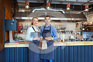 Smiling young man and woman using tablet at small eatery restaurant